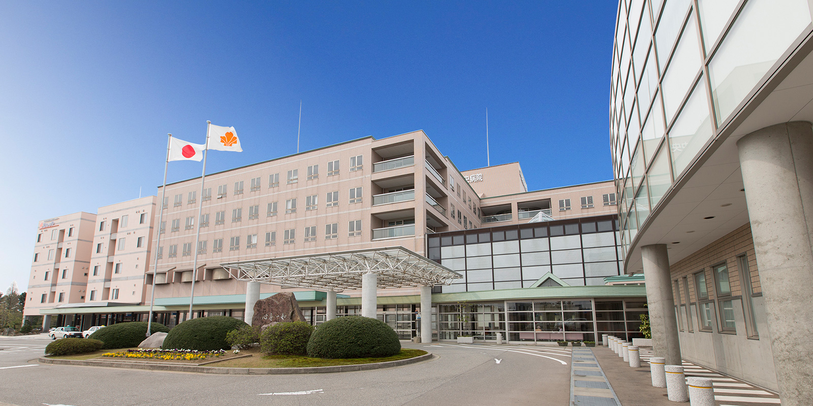 介護施設の建物外観。複数棟の近代的な建築と玄関前の広場。